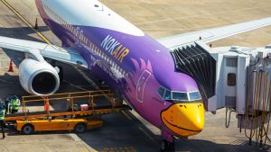 Nok Air airplane docked at an airport gate with vibrant livery and ground crew.